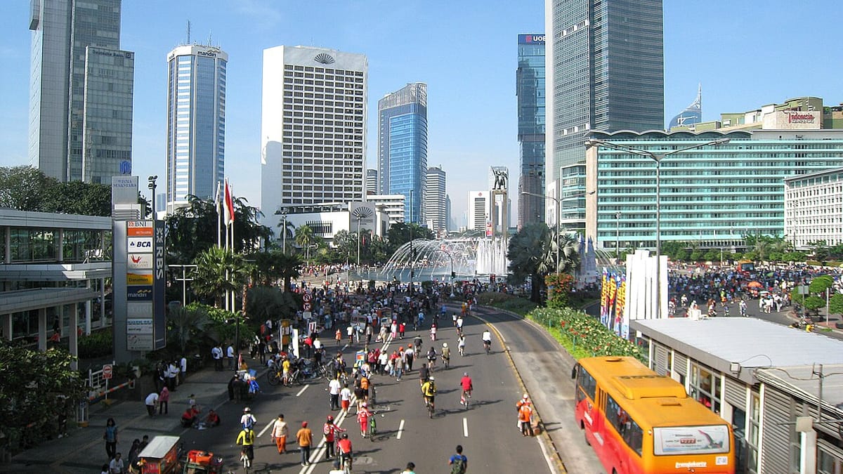 Warga bersepeda, berlari, dan berjalan kaki memenuhi jalan protokol Jakarta saat hari bebas kendaraan bermotor di antara gedung tinggi.