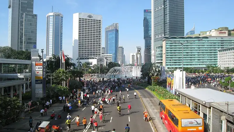 Warga bersepeda, berlari, dan berjalan kaki memenuhi jalan protokol Jakarta saat hari bebas kendaraan bermotor di antara gedung tinggi.
