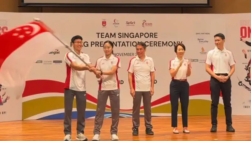 Kontingen Team Singapore mengibarkan bendera nasional di atas panggung acara serah terima bendera menjelang SEA Games 2025 Thailand