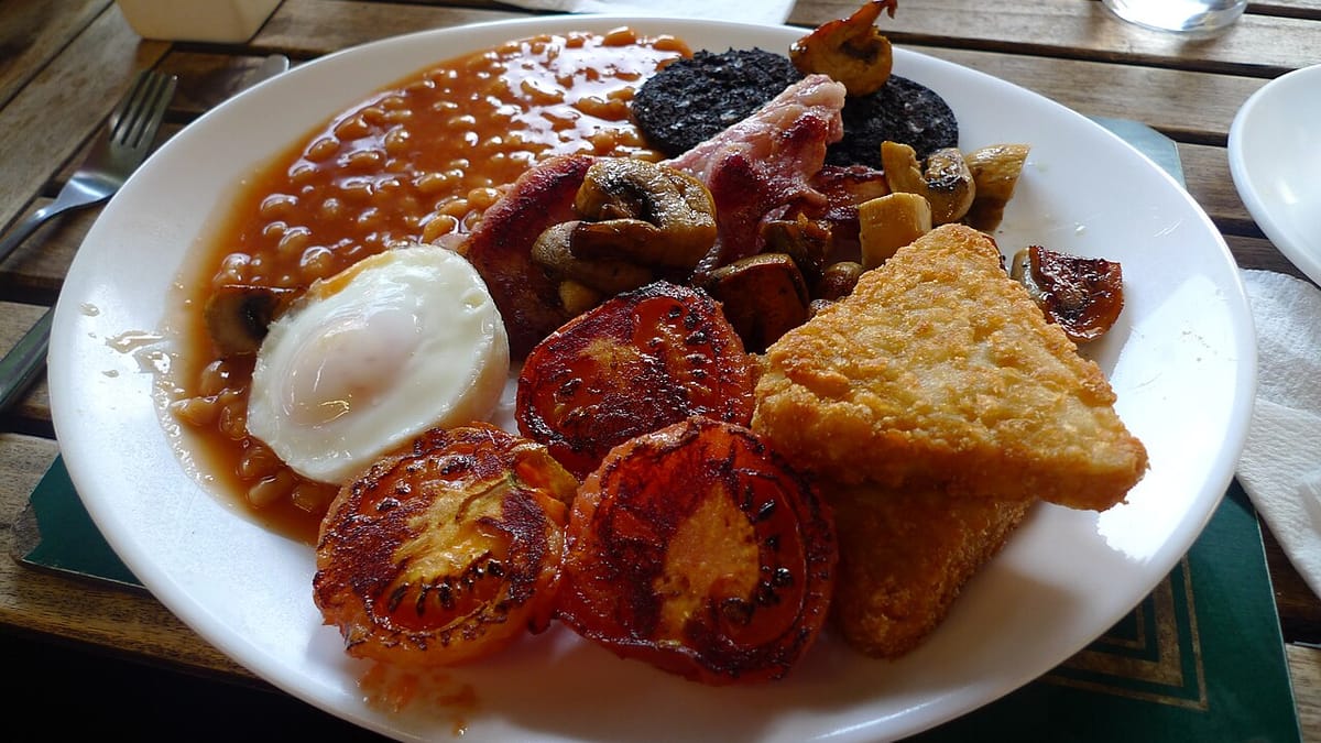 Sepiring sarapan berlemak berisi telur, kacang panggang saus tomat, bacon, sosis darah, jamur, tomat panggang, dan hash brown.