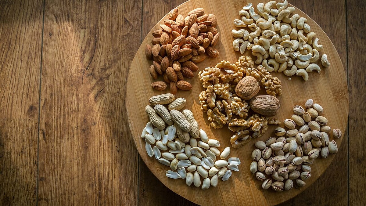 Aneka kacang seperti almon, kenari, mete, kacang tanah, dan pistachio dikelompokkan di atas talenan kayu bundar