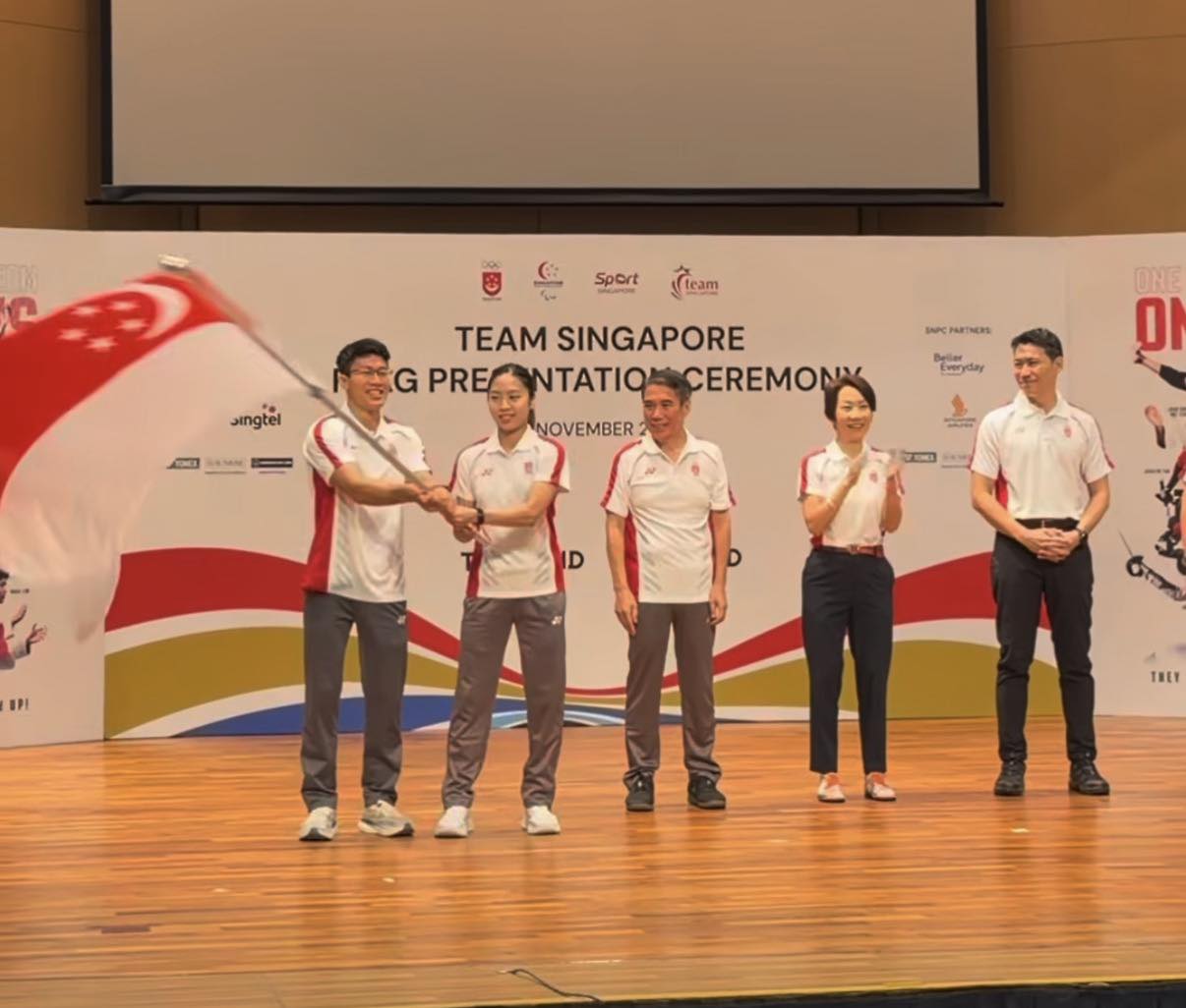 Kontingen Team Singapore mengibarkan bendera nasional di atas panggung acara serah terima bendera menjelang SEA Games 2025 Thailand