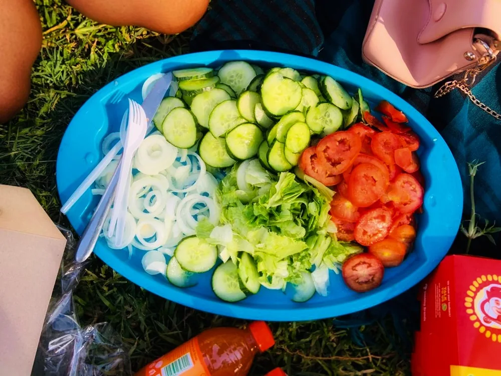 Irisan mentimun, tomat, bawang, dan selada disusun di atas nampan biru.