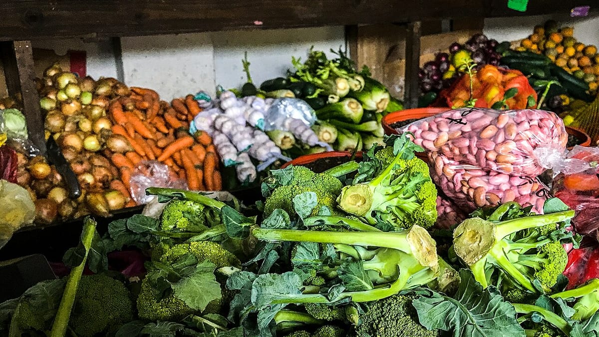 Aneka sayuran segar seperti brokoli, wortel, bawang bombai, bawang putih, dan kacang merah tertata di lapak pasar.